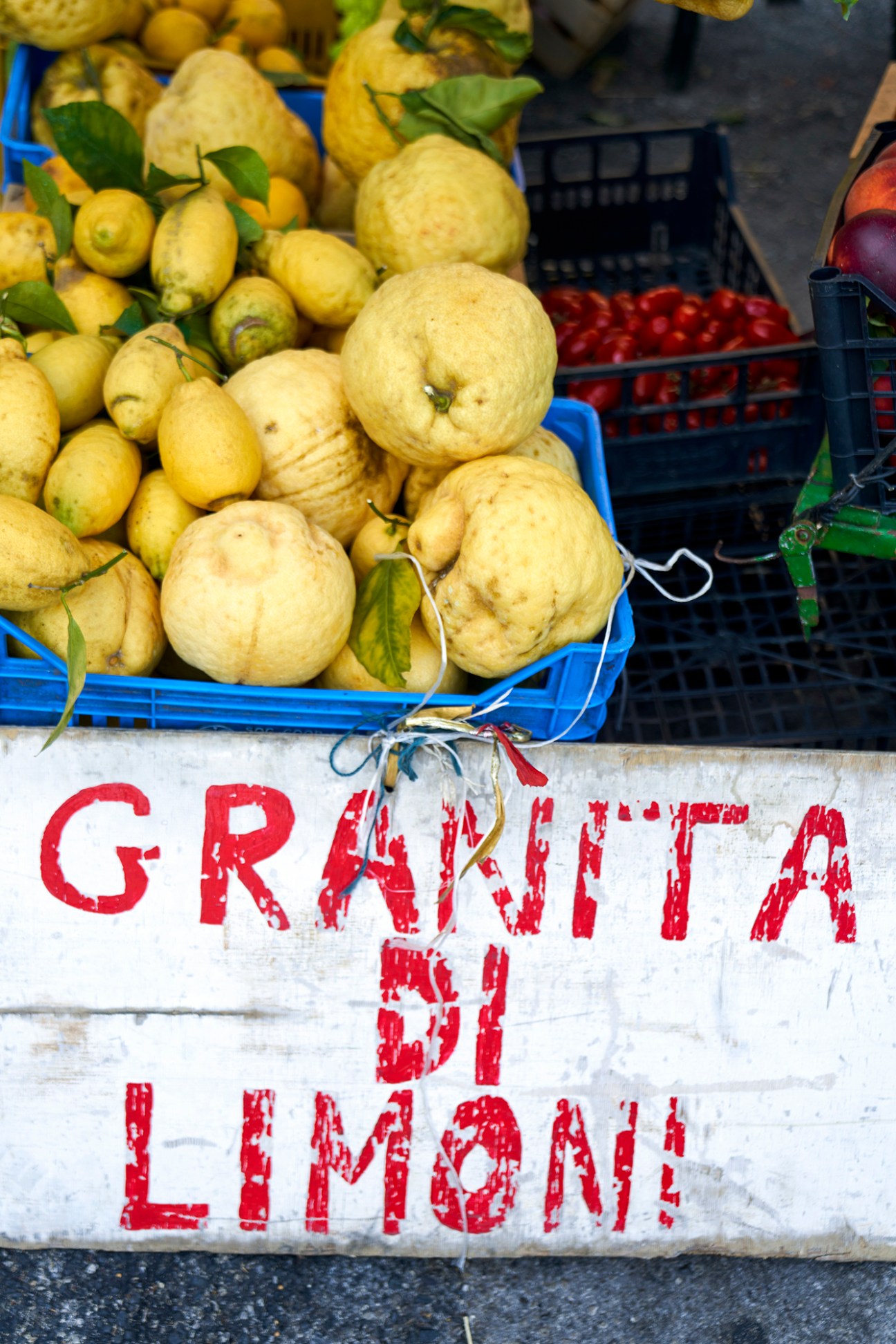 Display of citrus fruits including lemons at an Italian market stall with 'GRANITA DI LIMONI' sign