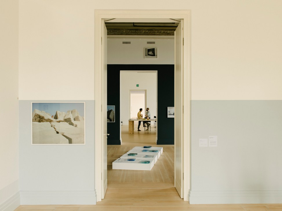 Museum gallery space with wooden floors showing visitors viewing contemporary art exhibition
