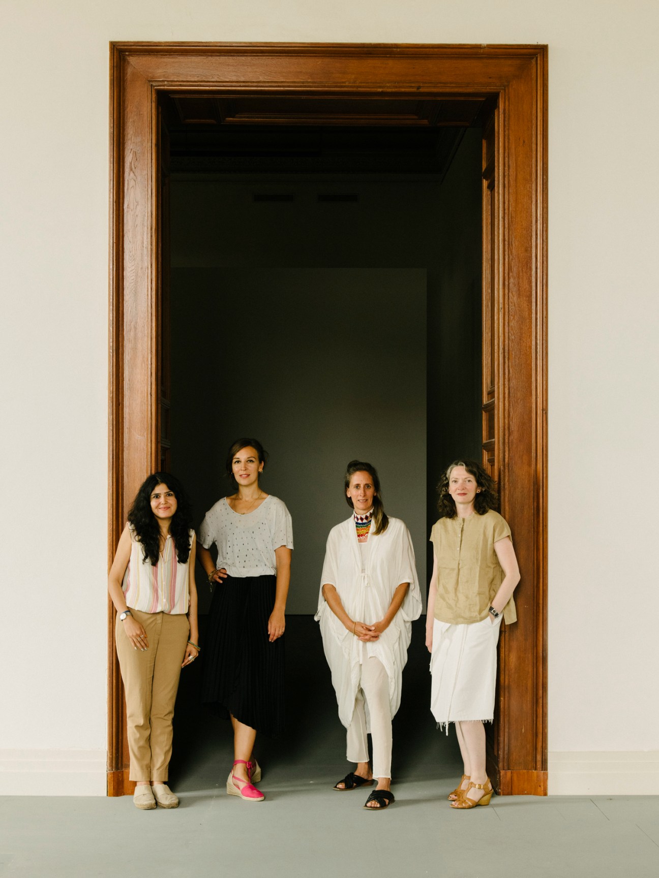 Four women standing together in bright museum space with classical architecture and natural lighting