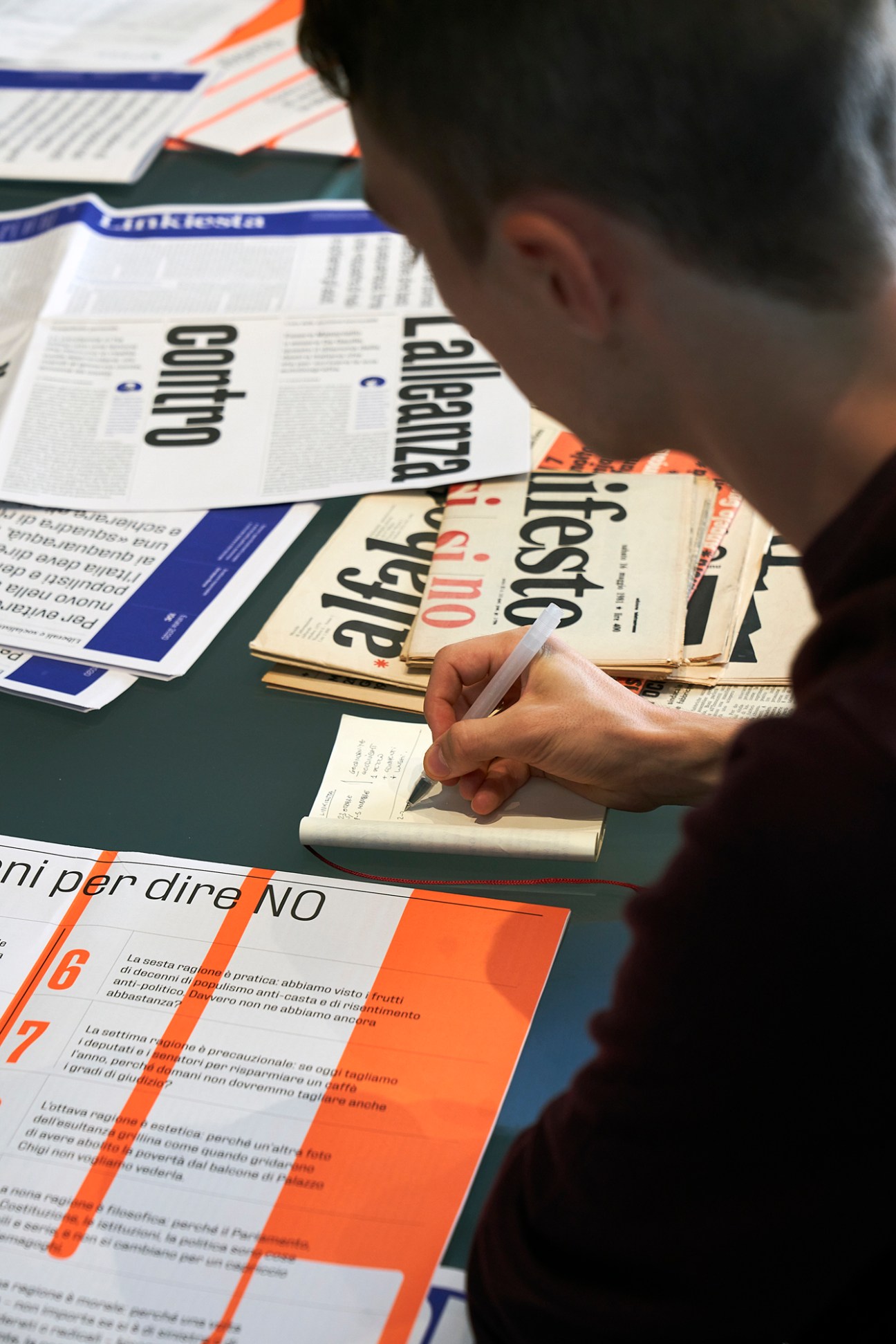 Person reviewing newspaper pages with 1970s-inspired design featuring bold typography and orange and blue accents