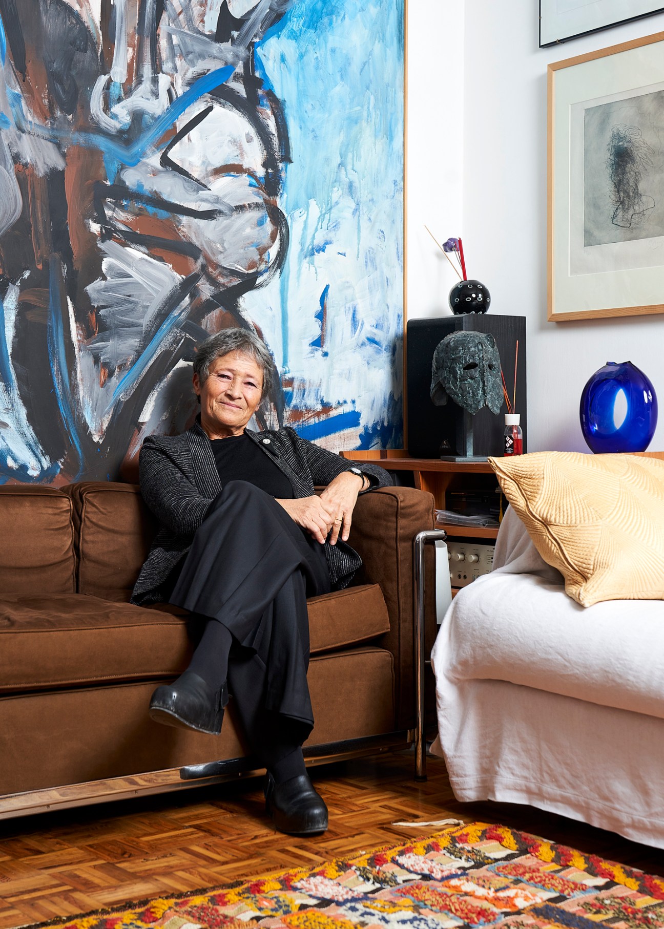 Chiara Mazzoleni sits on a brown leather sofa in front of an abstract blue and white painting in her Venice home.