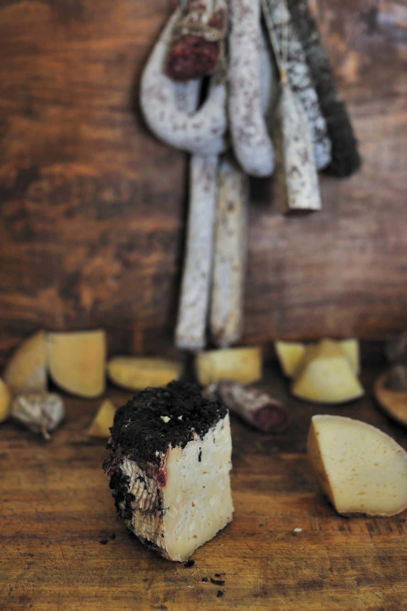 Sliced aged organic brigantaccio pecorino cheese with rind on wooden surface.