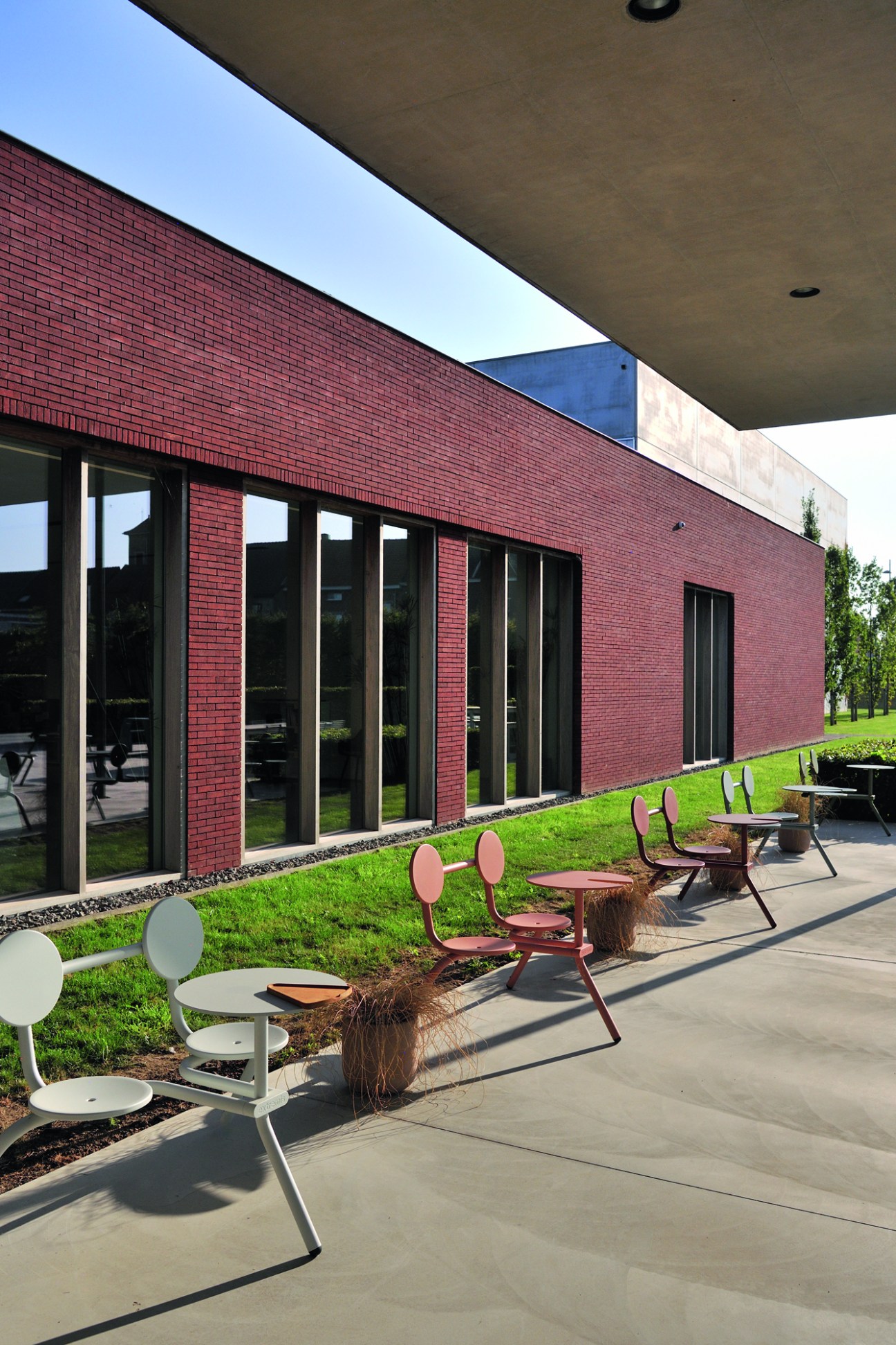 Modern brick office building with large windows and outdoor furniture displayed on concrete terrace