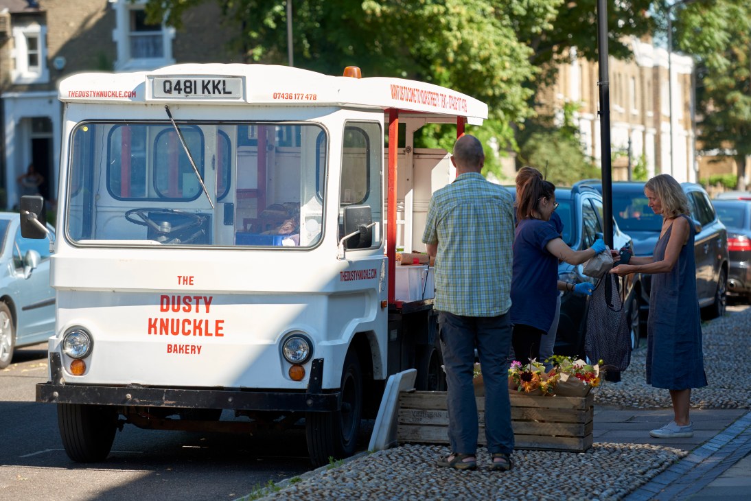 The Dusty Knuckle bakery's converted white milk float van serving customers on a London street