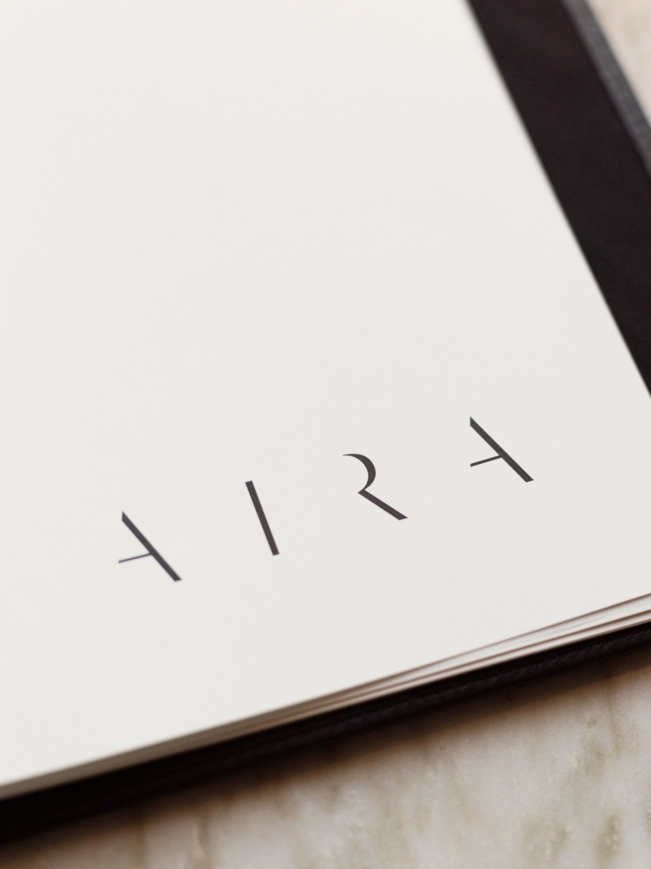 Close-up of white paper or napkin with AIRA text printed in minimalist typography