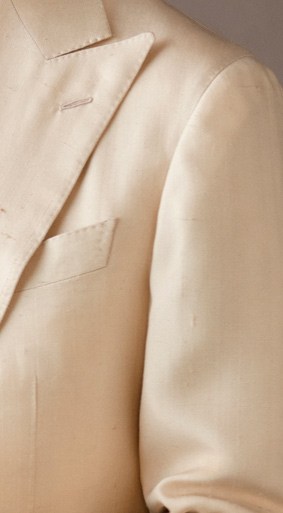 Close-up detail of beige suit lapel showing construction and tailoring details