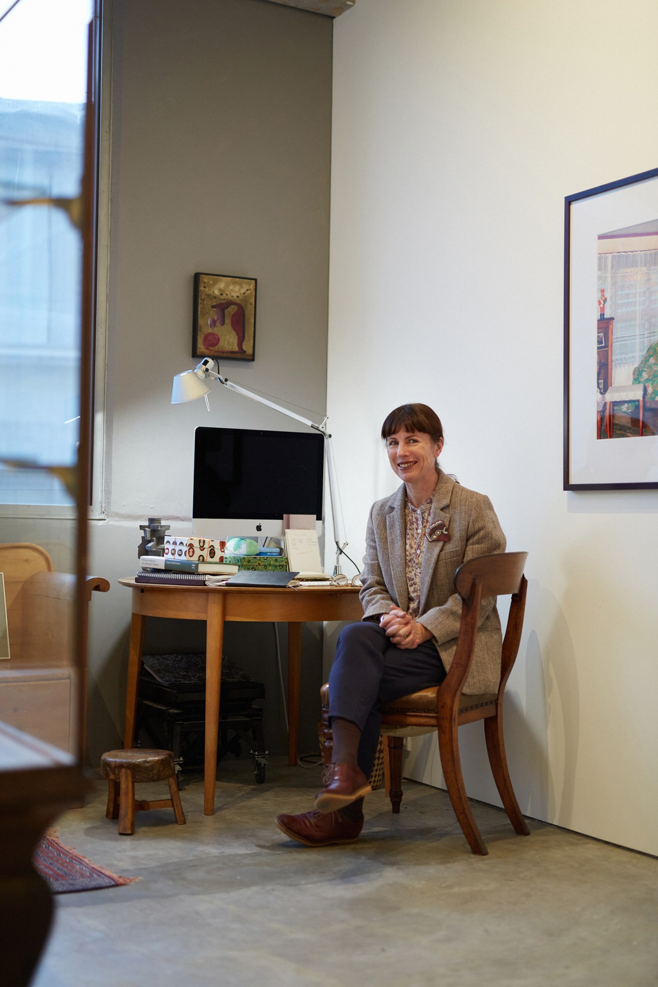 Gallerist Anna Miles sitting at a wooden desk with a computer in her apartment gallery space.