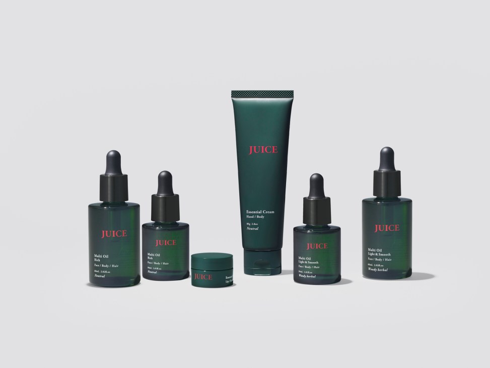 Collection of Juice skincare products in dark green bottles and tubes arranged on neutral background