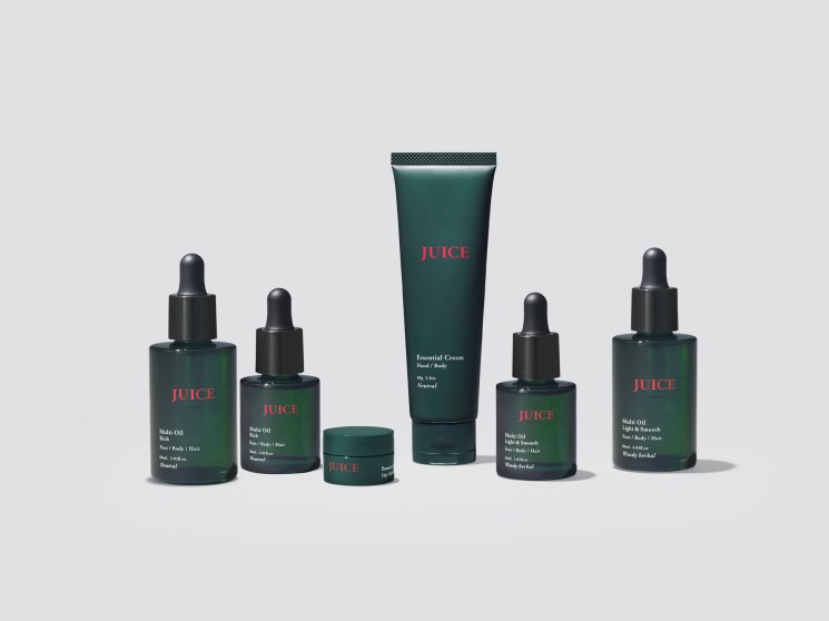 Collection of Juice skincare products in dark green bottles and tubes arranged on neutral background