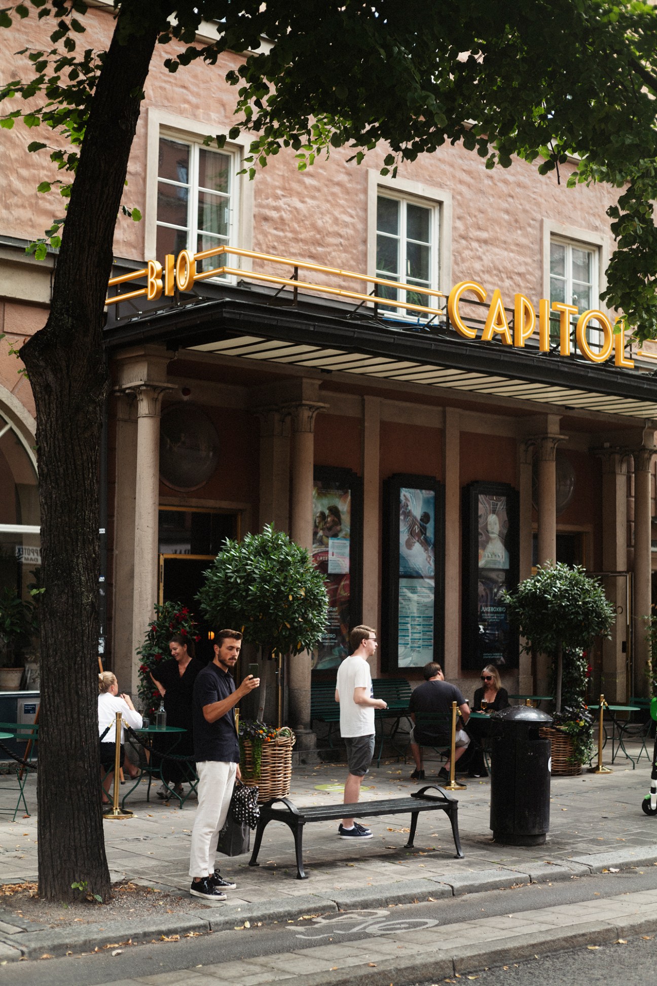 Exterior view of Capitol Bio cinema in Stockholm with patrons gathered outside under tree-lined street