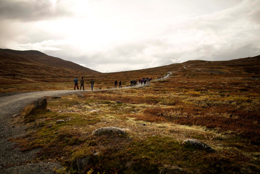A group of hikers walking across a barren, mountainous Norwegian landscape with moss and sparse vegetation.