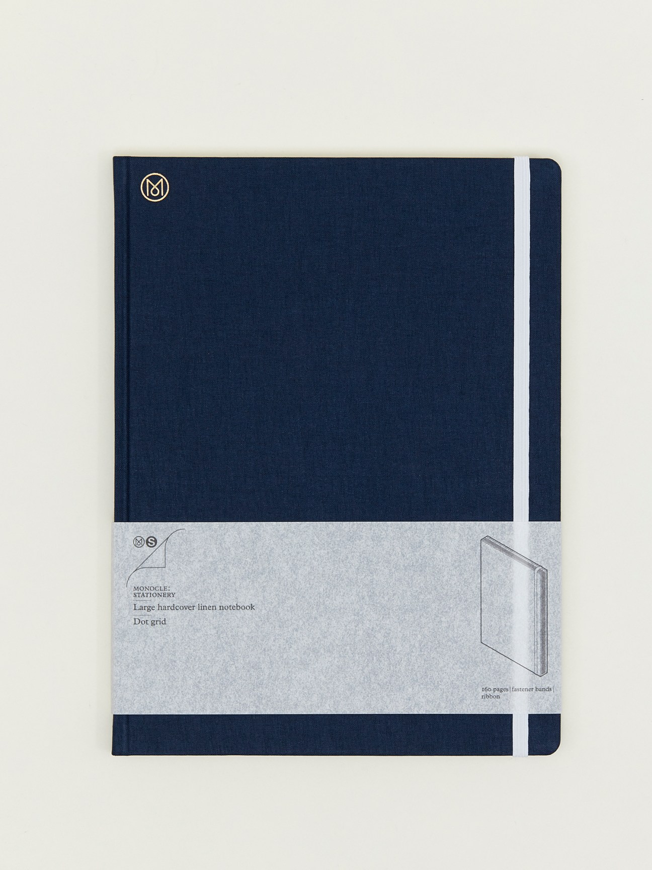 Monocle large hardcover linen notebook in navy with white elastic band and ribbon.