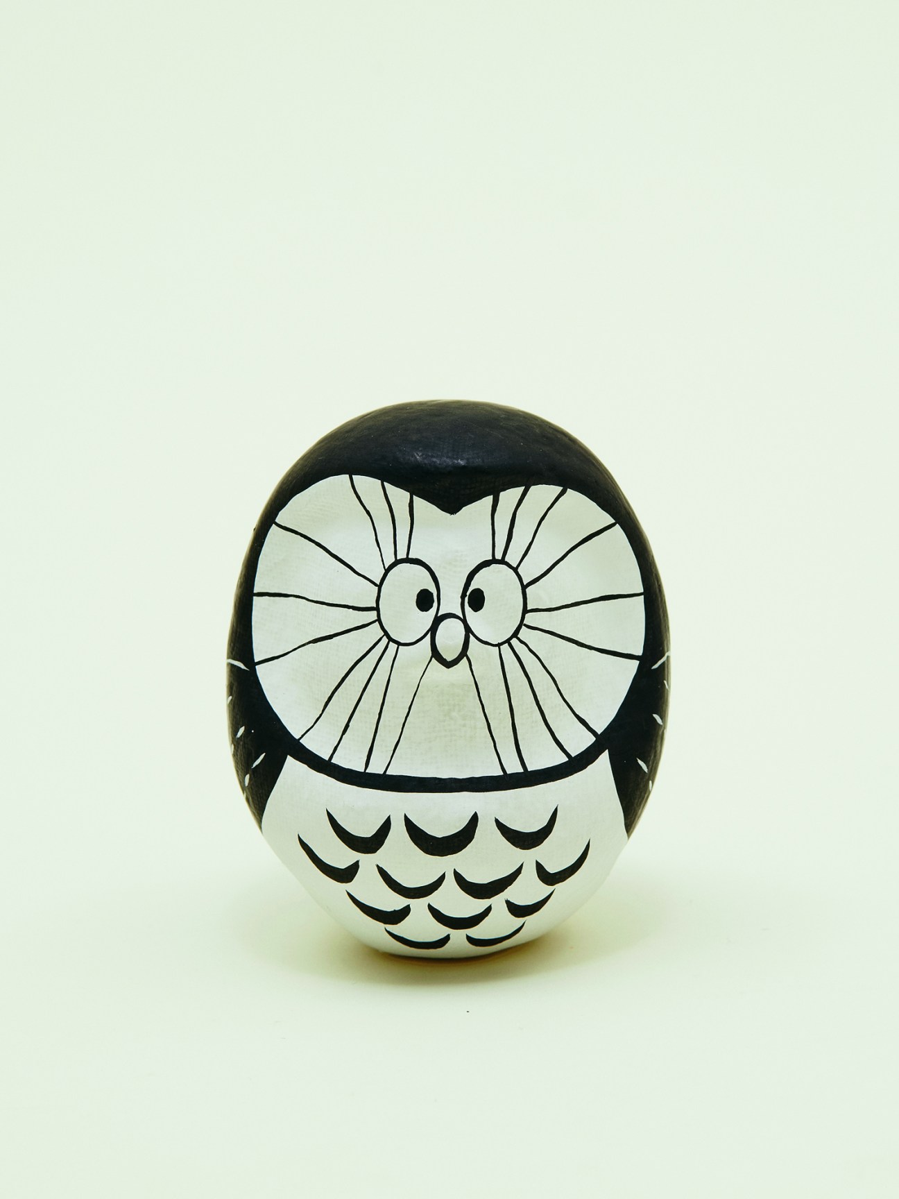 Monochan daruma, a black and white owl-shaped ceramic figurine with radiating line details.