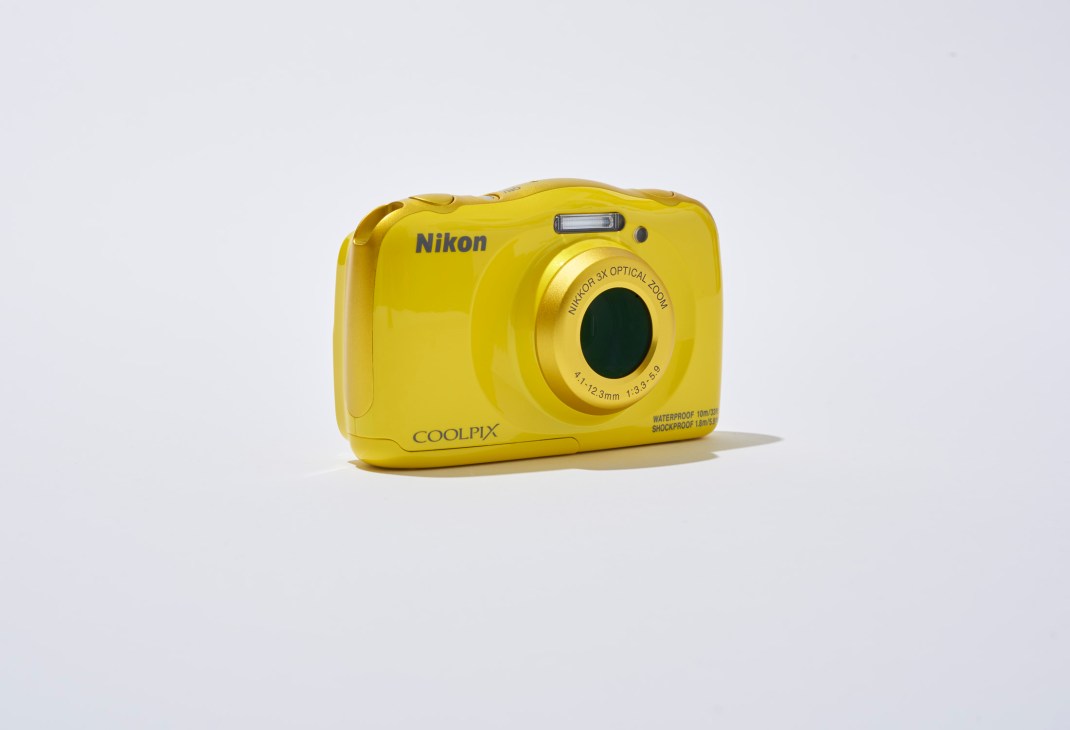 Yellow Nikon Coolpix waterproof digital camera with 3x optical zoom against a light grey background.