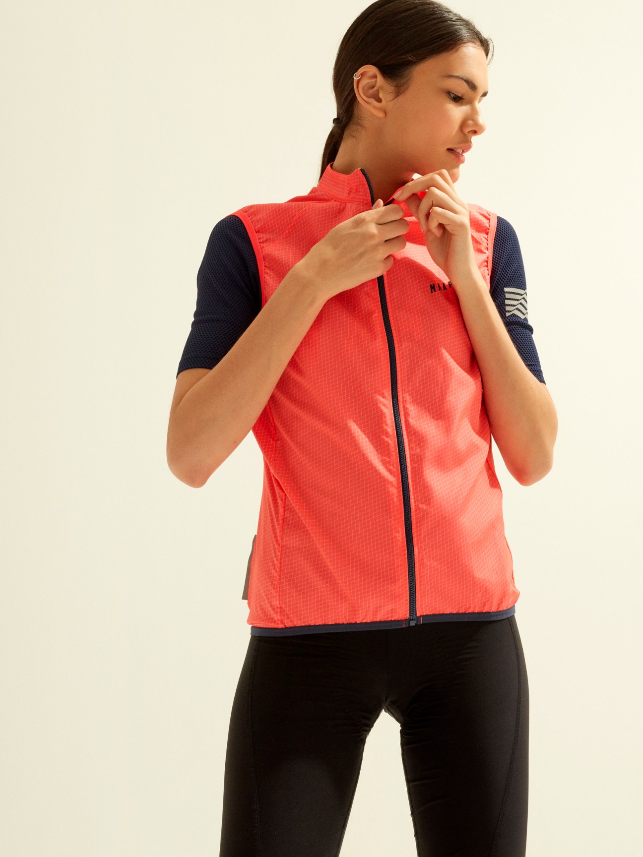 Woman wearing Maap red cycling vest with navy sleeves and black leggings