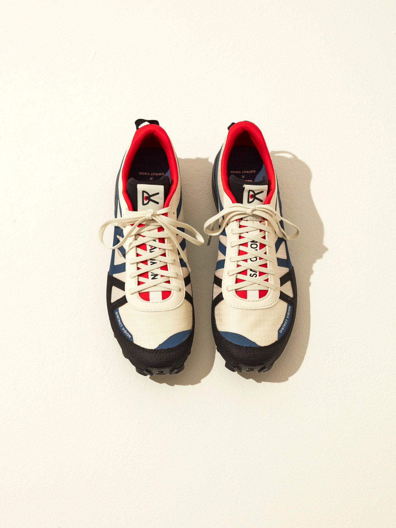 District Vision x Salomon S-Lab running shoes in cream, navy, and red with red laces displayed from above.