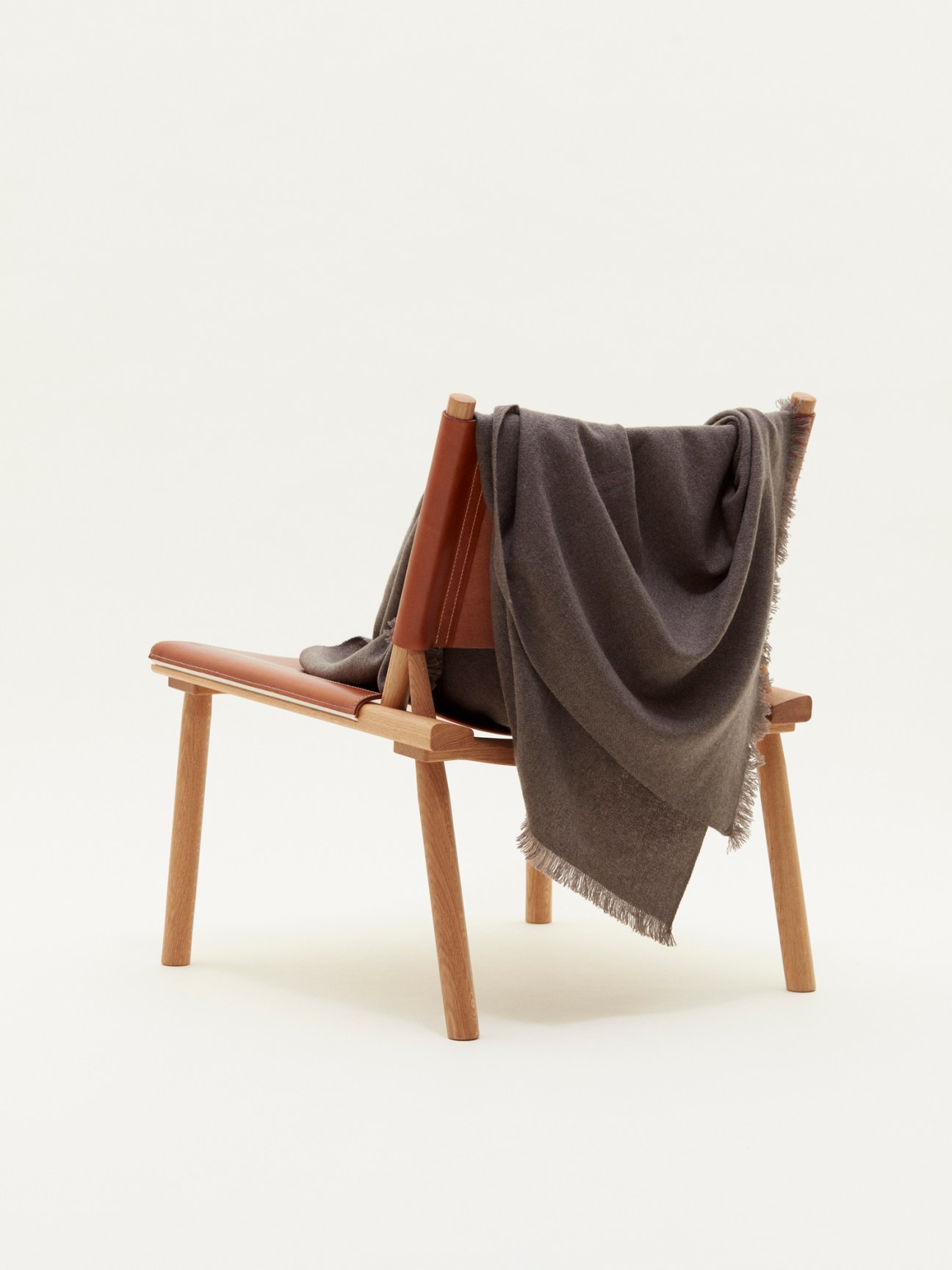 Grey yak wool blanket draped over wooden chair with leather seat
