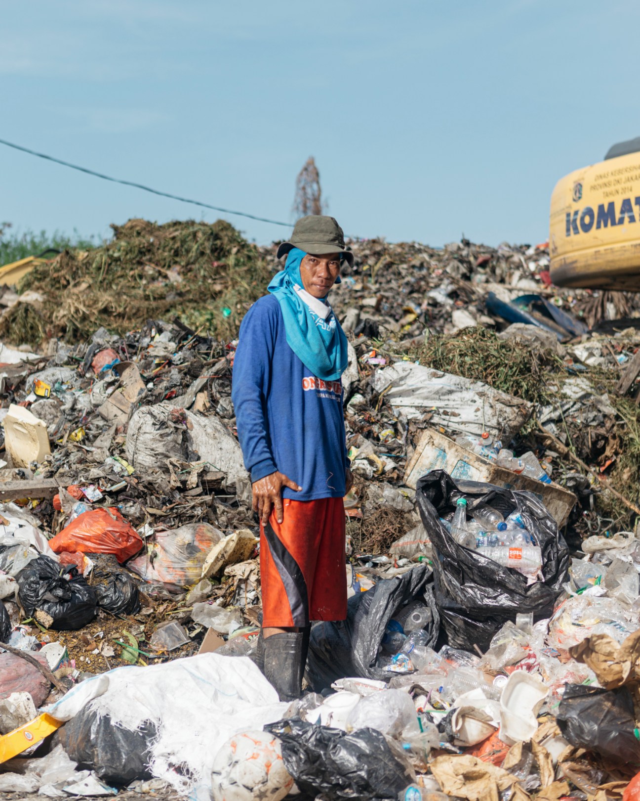 Worker in blue jacket scavenging at a temporary rubbish dump in Puit, north Jakarta.