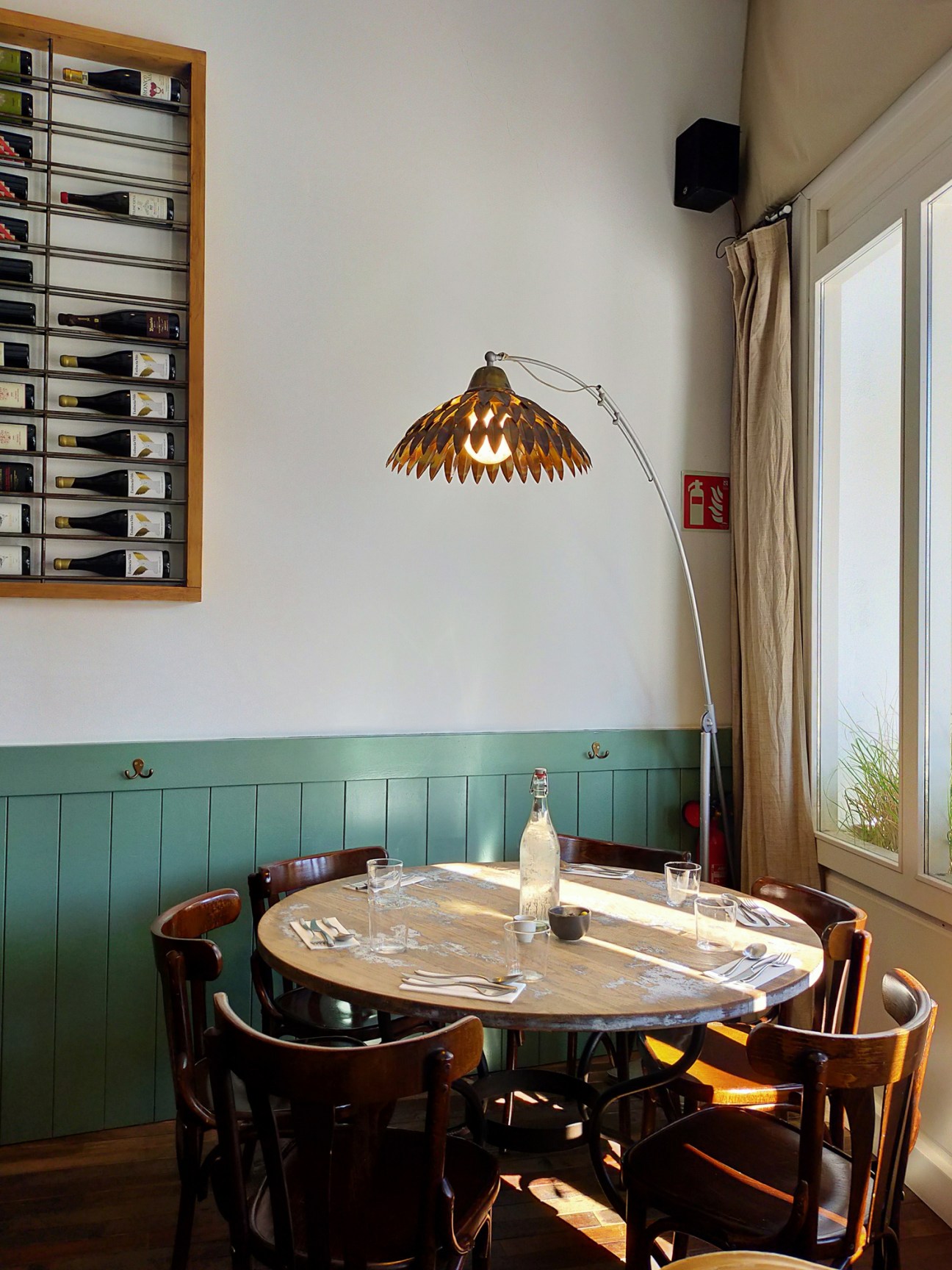 Restaurant interior with round wooden table, bentwood chairs, and green wainscoting at Agreste de Fabio
