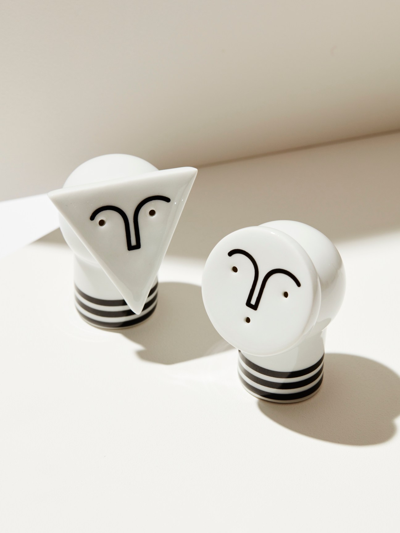 White ceramic salt and pepper shakers shaped like lightbulbs with simple face designs