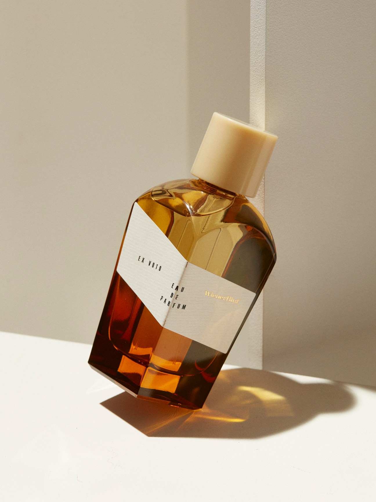 Amber-colored perfume bottle with beige cap and white label reading Wienerblut eau de parfum