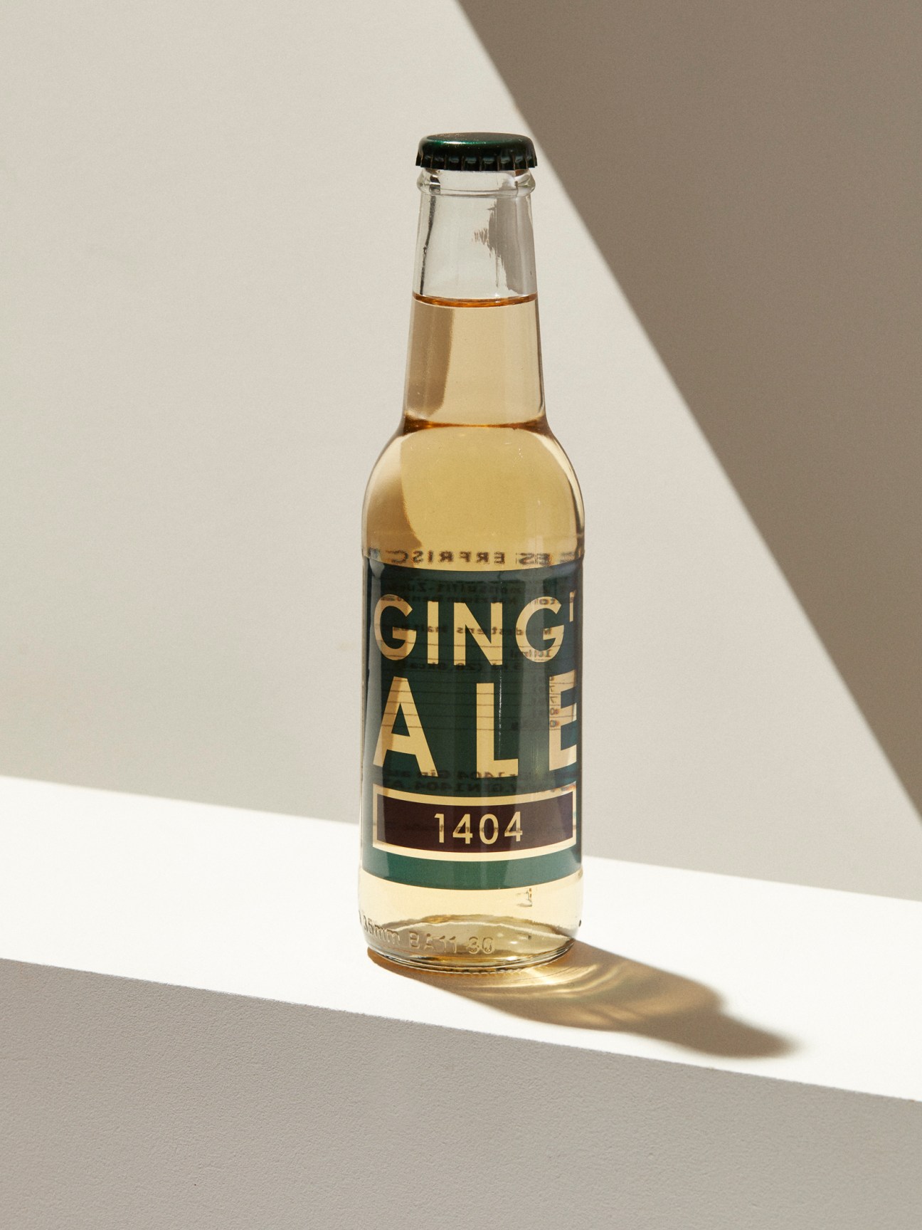Clear glass bottle of ginger ale with green and gold label reading GINGER ALE 1404