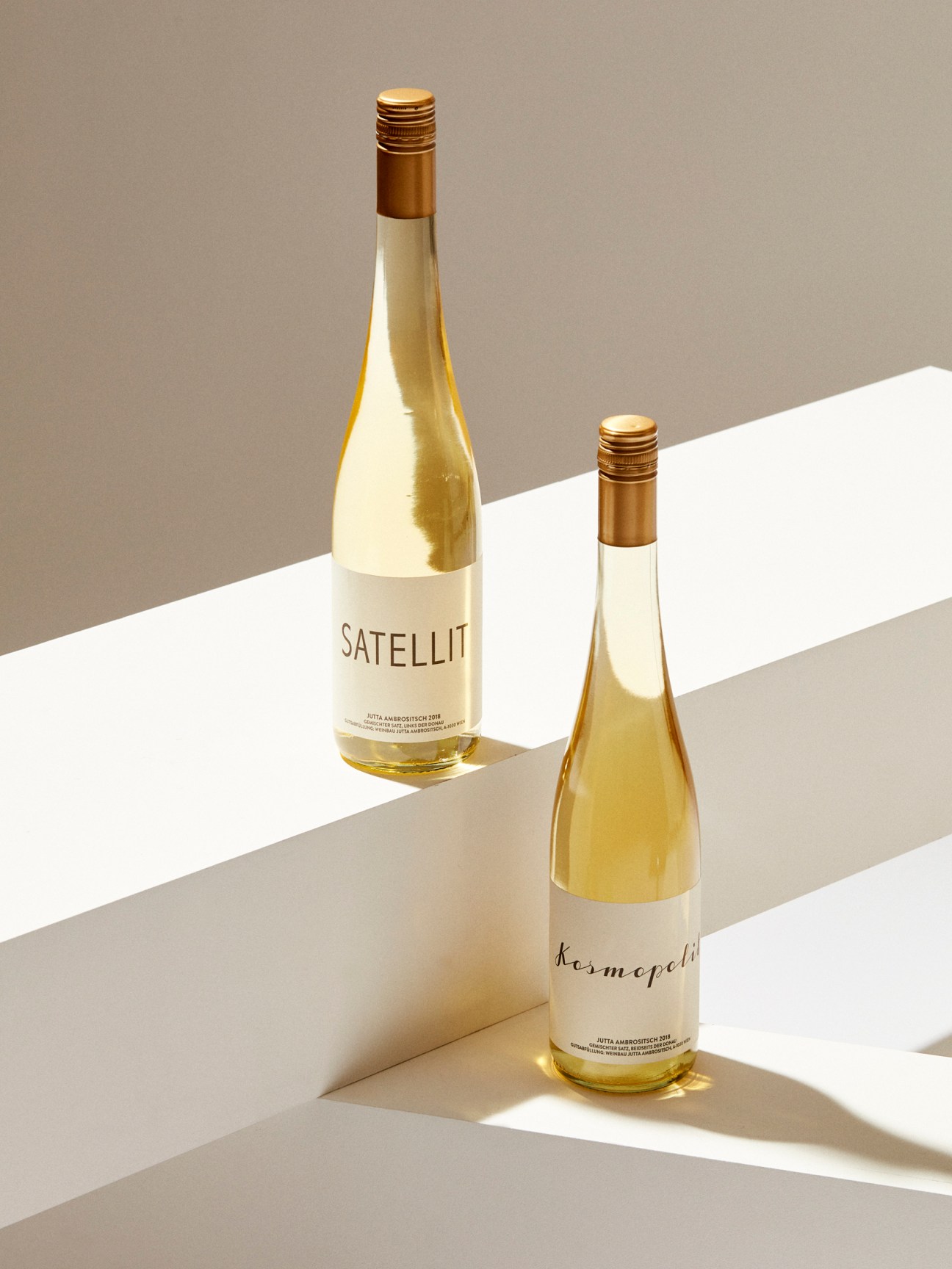 Two wine bottles with golden tops and white labels displaying Satellit and Kermöpelt branding