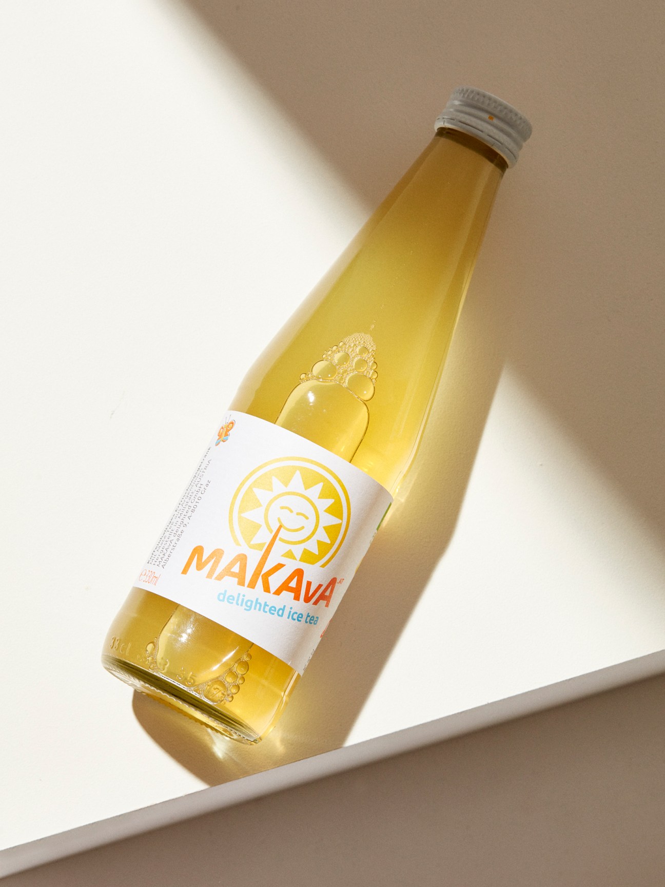 Glass bottle of Makava delighted ice tea with white label and yellow sun logo