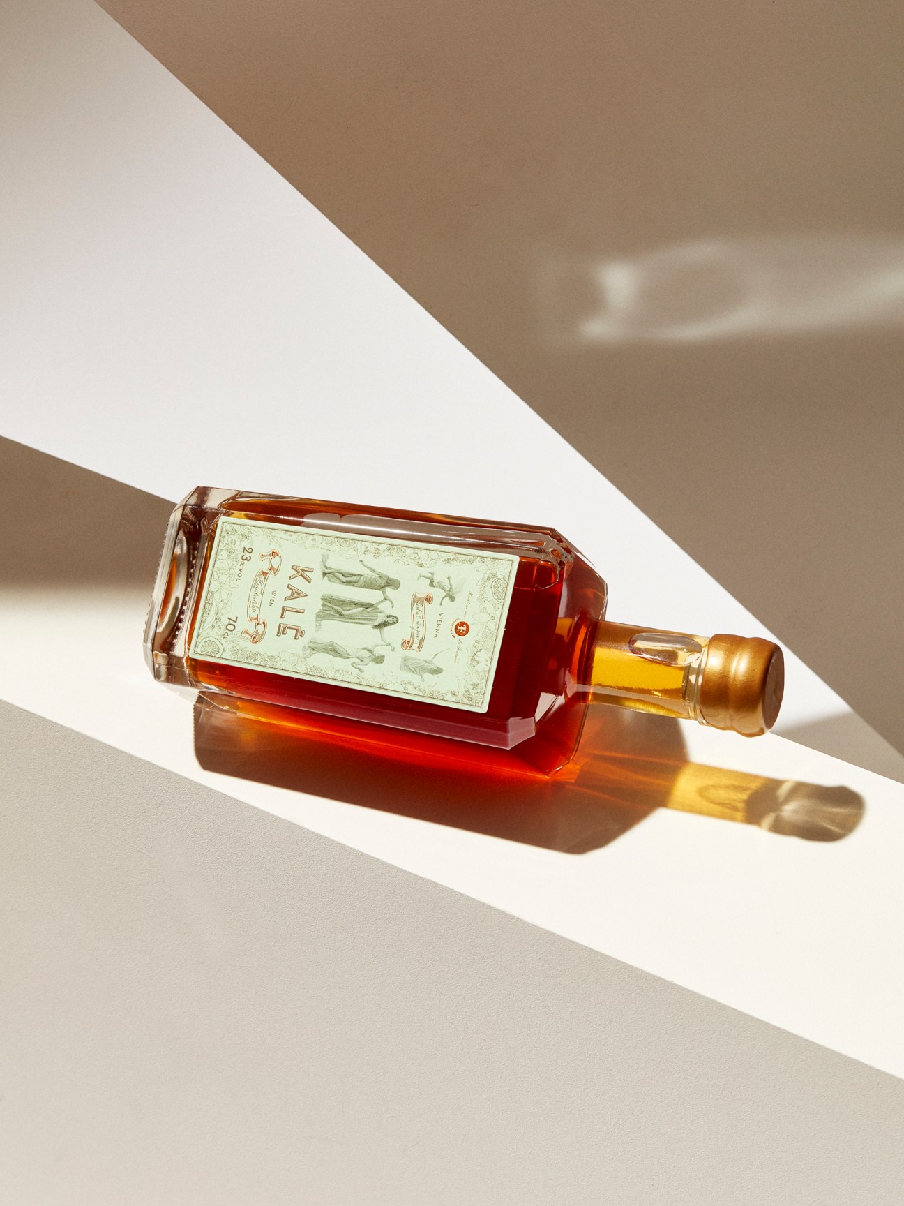 Amber-colored herbal liqueur bottle with white label on white surface