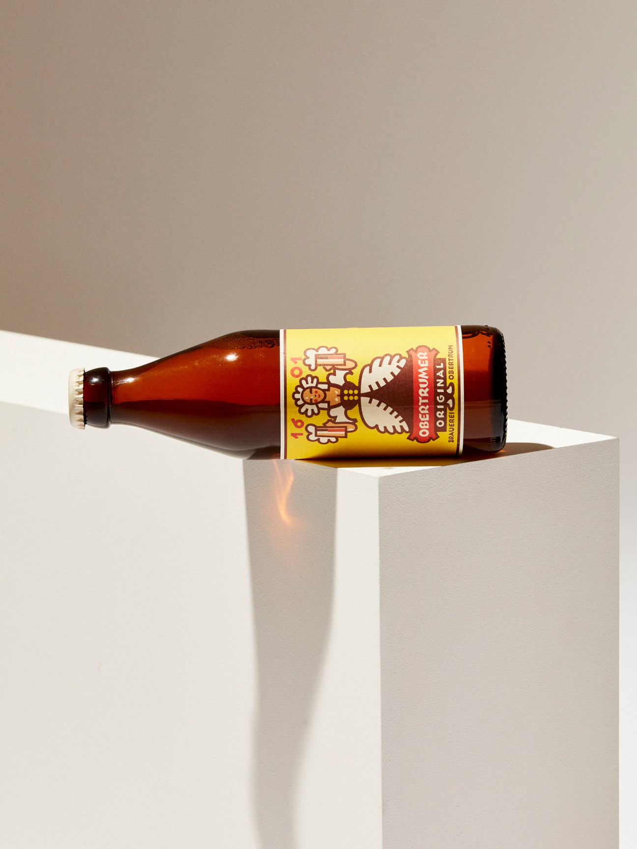Märzen-Zwickl beer bottle by Trumer with yellow label on white display surface