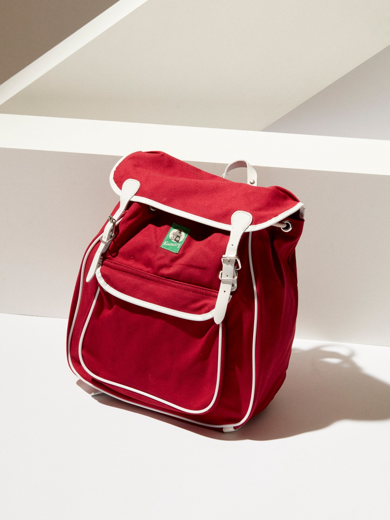 Red canvas backpack with white leather straps and buckles from Kamarg