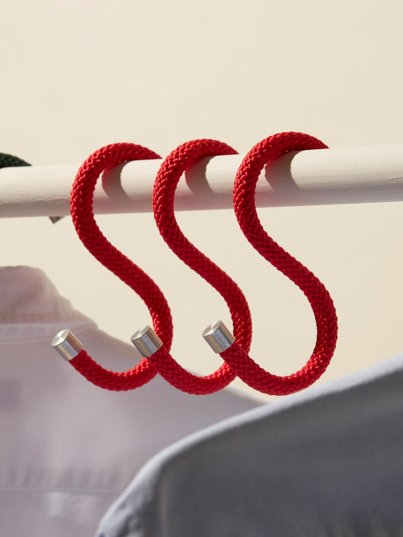 Three red rope S-hooks hanging from a white closet rod