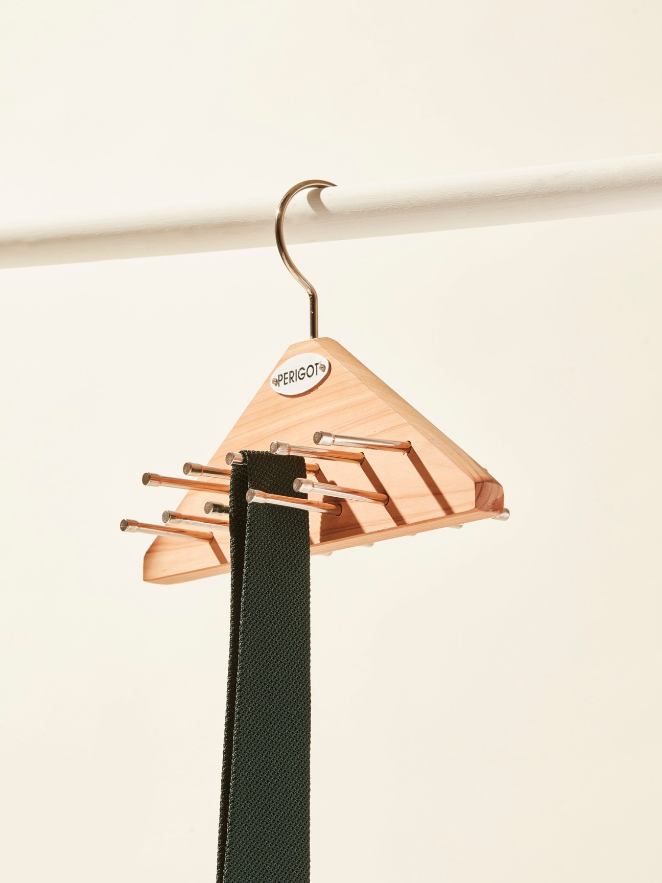Wooden tie hanger with multiple horizontal rods holding a dark green tie, hanging from a closet rod