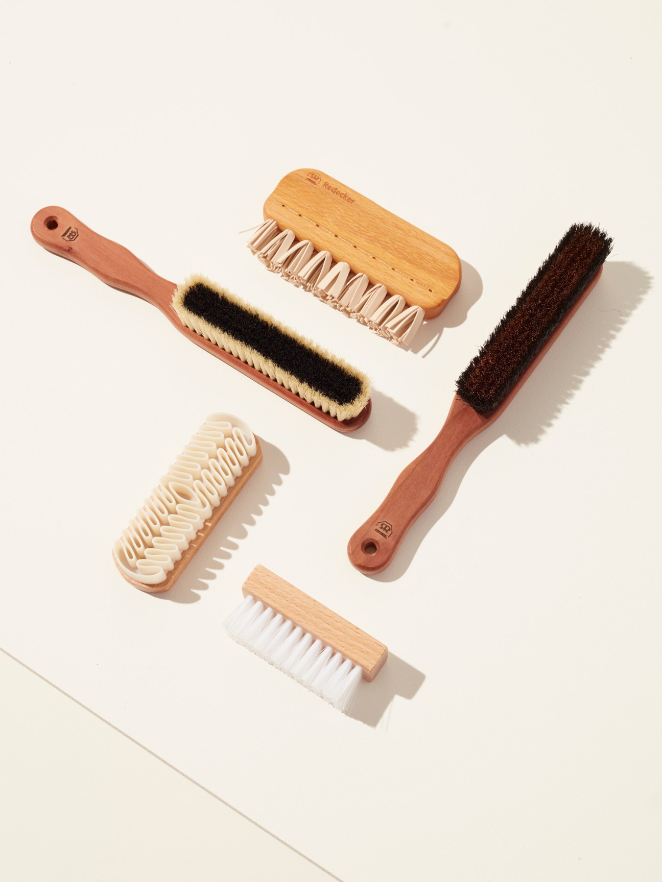 Six wooden and natural bristle brushes for clothing care arranged on white background