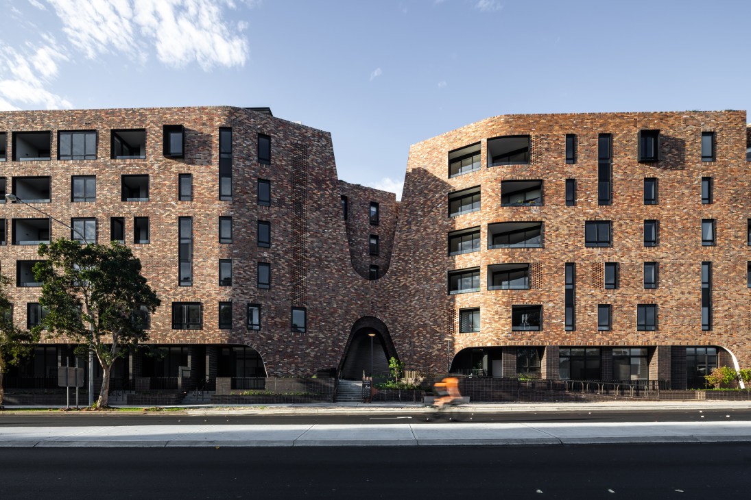 Modern brick apartment building facade with irregular window pattern and varied brick tones
