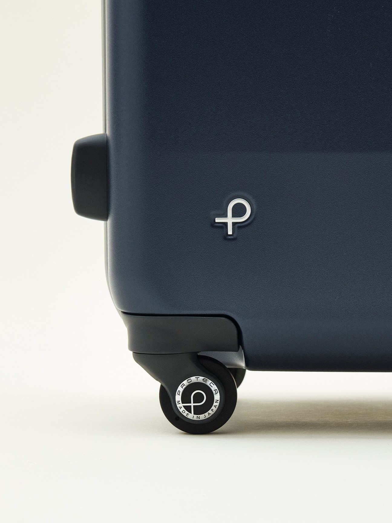 Detail of Proteca Equinox Light U navy suitcase showing logo and wheel.