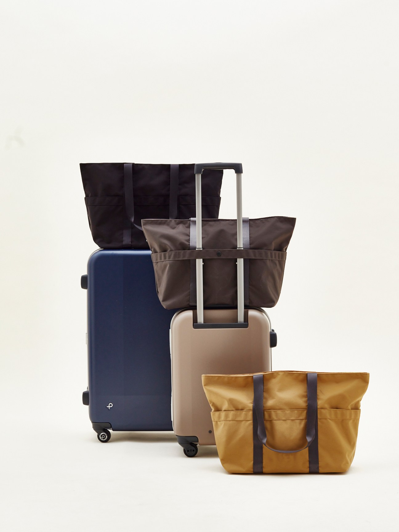 Collection of Monocle travel bags and suitcases in various colors including tote bags and wheeled luggage
