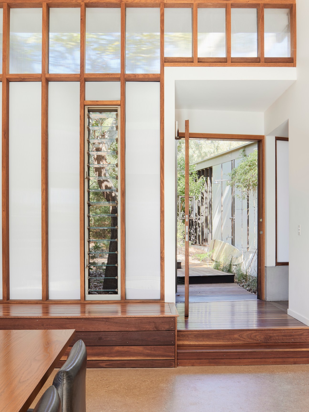 Modern interior with wooden grid window system, polished concrete floors, and view to outdoor terrace