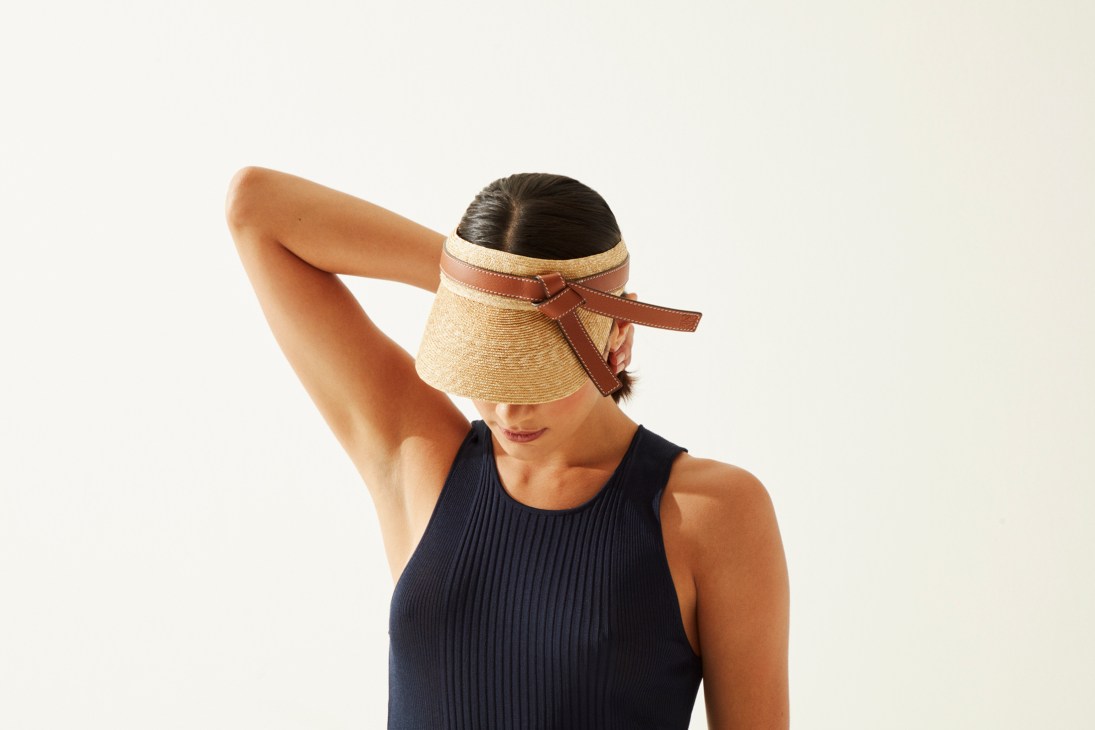 Woman wearing navy ribbed vest and straw visor with brown leather trim