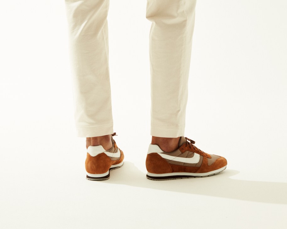 Person wearing cream trousers and brown and white Reproduction of Found trainers.