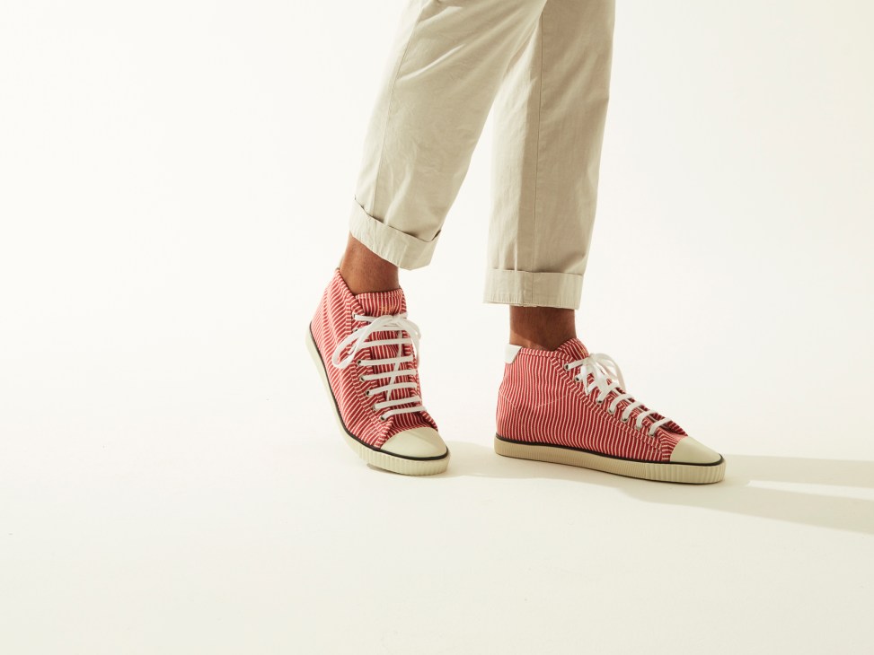 Person wearing cream trousers and red-and-white striped high-top trainers by Celine.