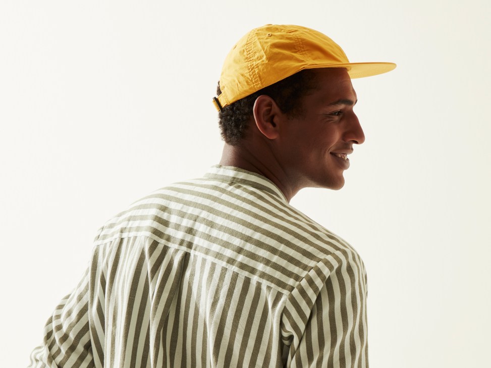 Man in profile wearing striped shirt and yellow cap by Marrakshi Life and Sublime.