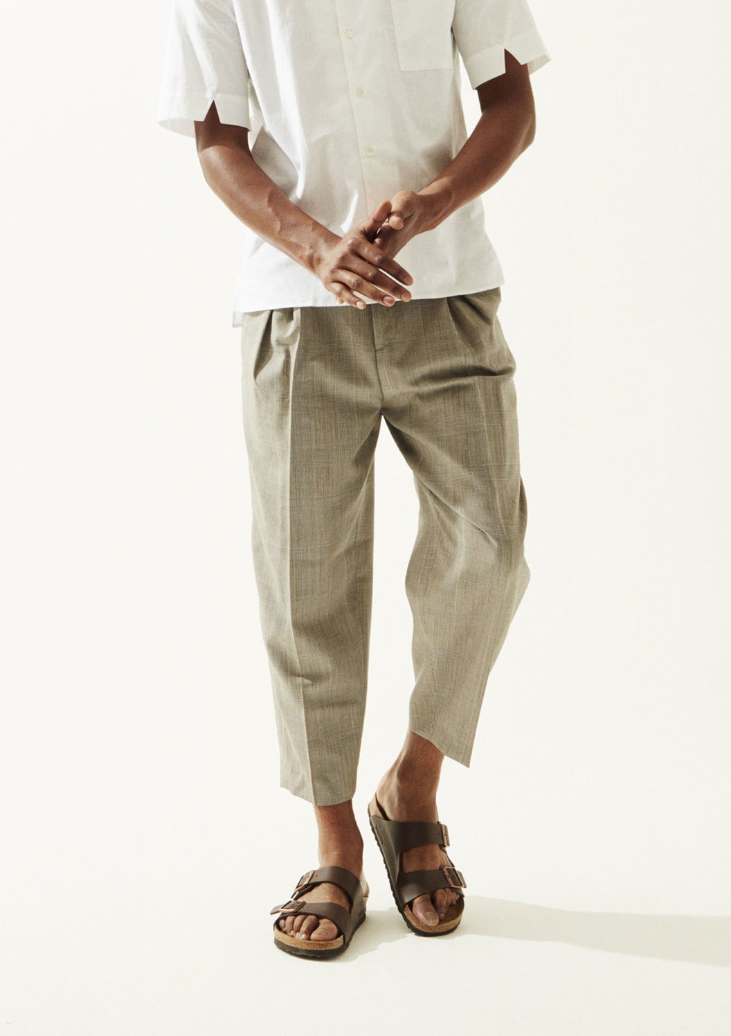 Man wearing a cream linen shirt and beige trousers by École de Pensée with Birkenstock sandals.