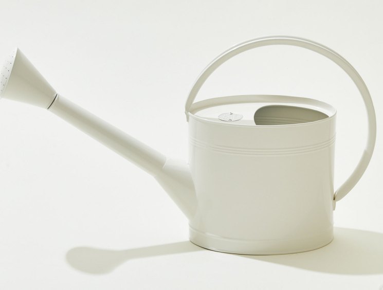 White galvanised steel watering can with powder coating and curved handle against light background