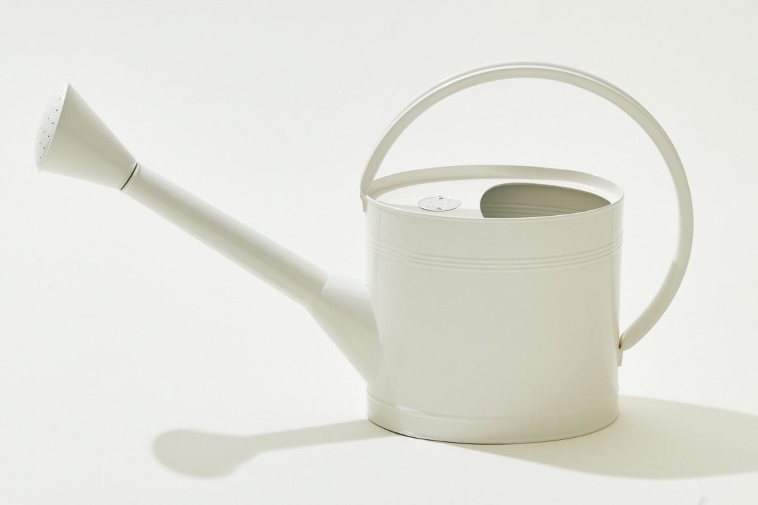 White galvanised steel watering can with powder coating and curved handle against light background