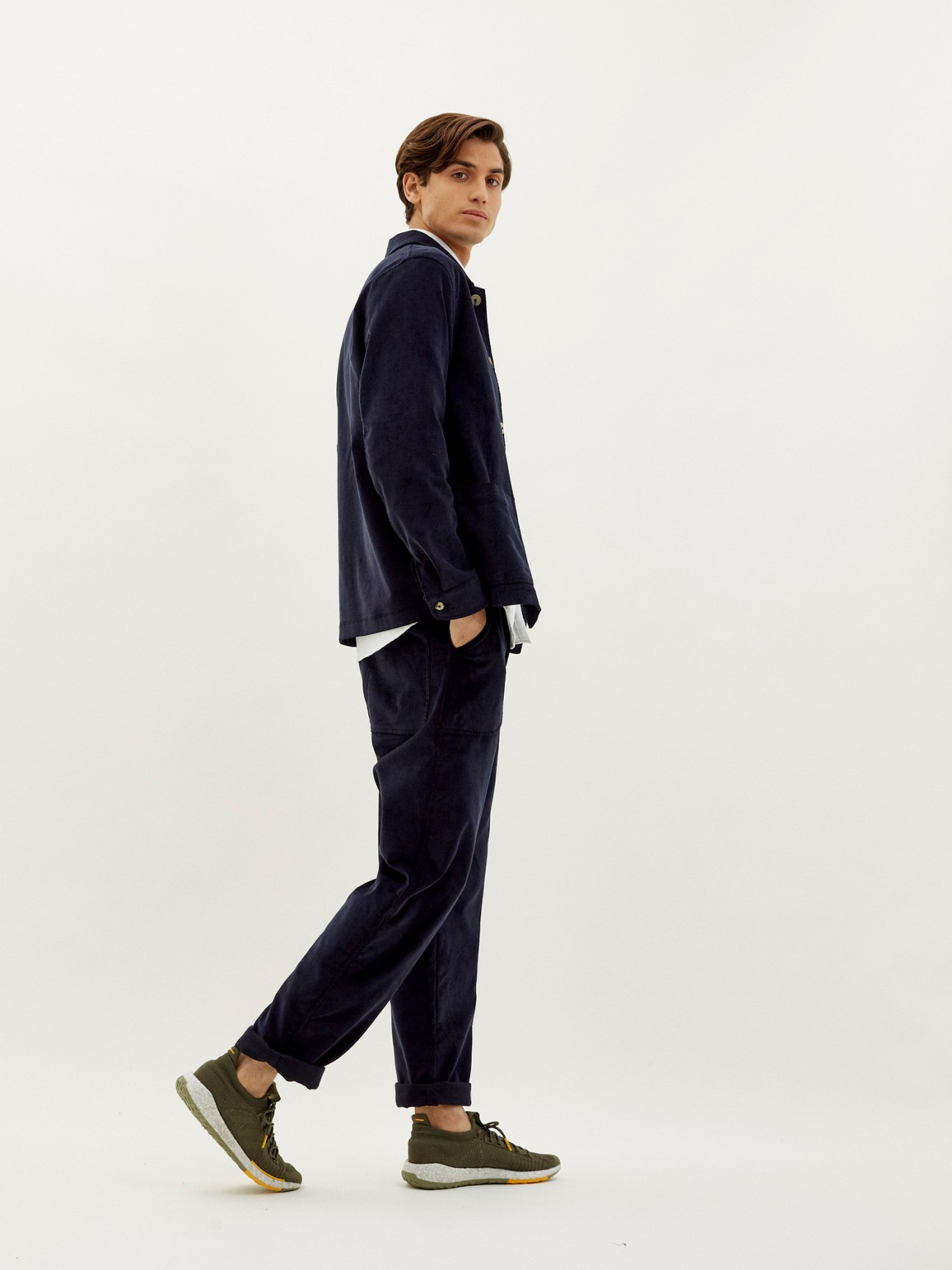 Man wearing fine corduroy work jacket and trousers by De Bonne Facture x Monocle with olive trainers.
