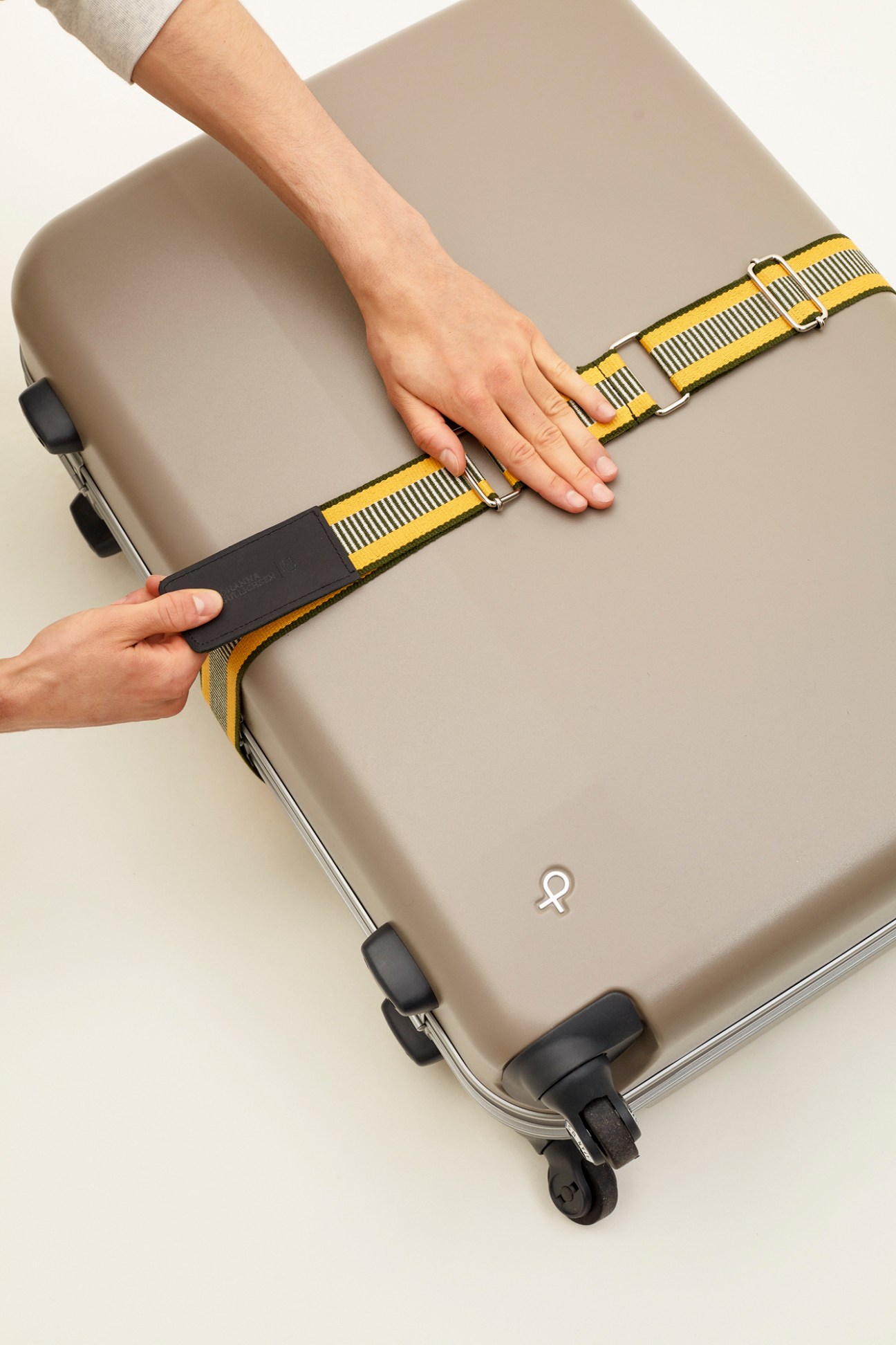 Johanna Gullichsen x Monocle yellow luggage belt with pouch attached to suitcase