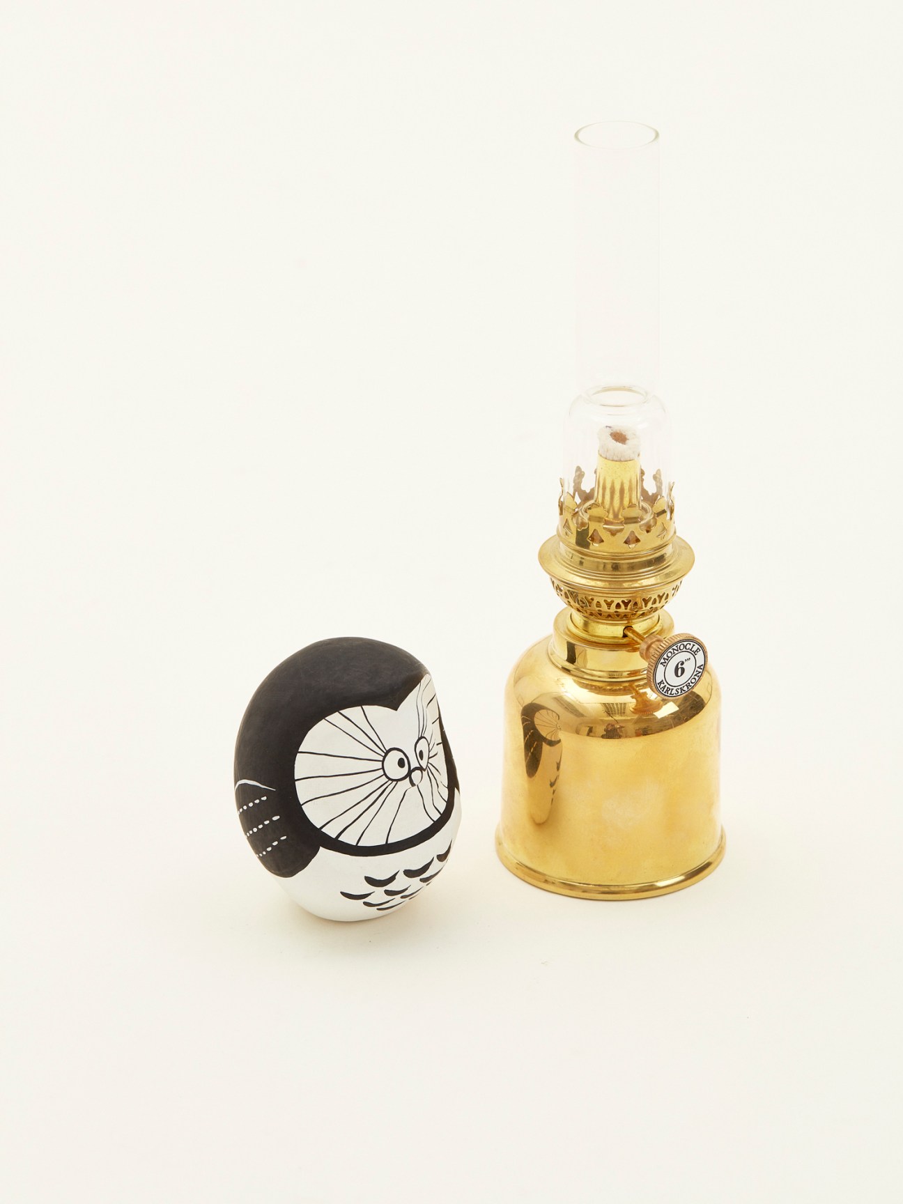 Karlskrona Lampfabrik x Monocle brass oil lamp with glass chimney displayed with Monochan Daruma figure