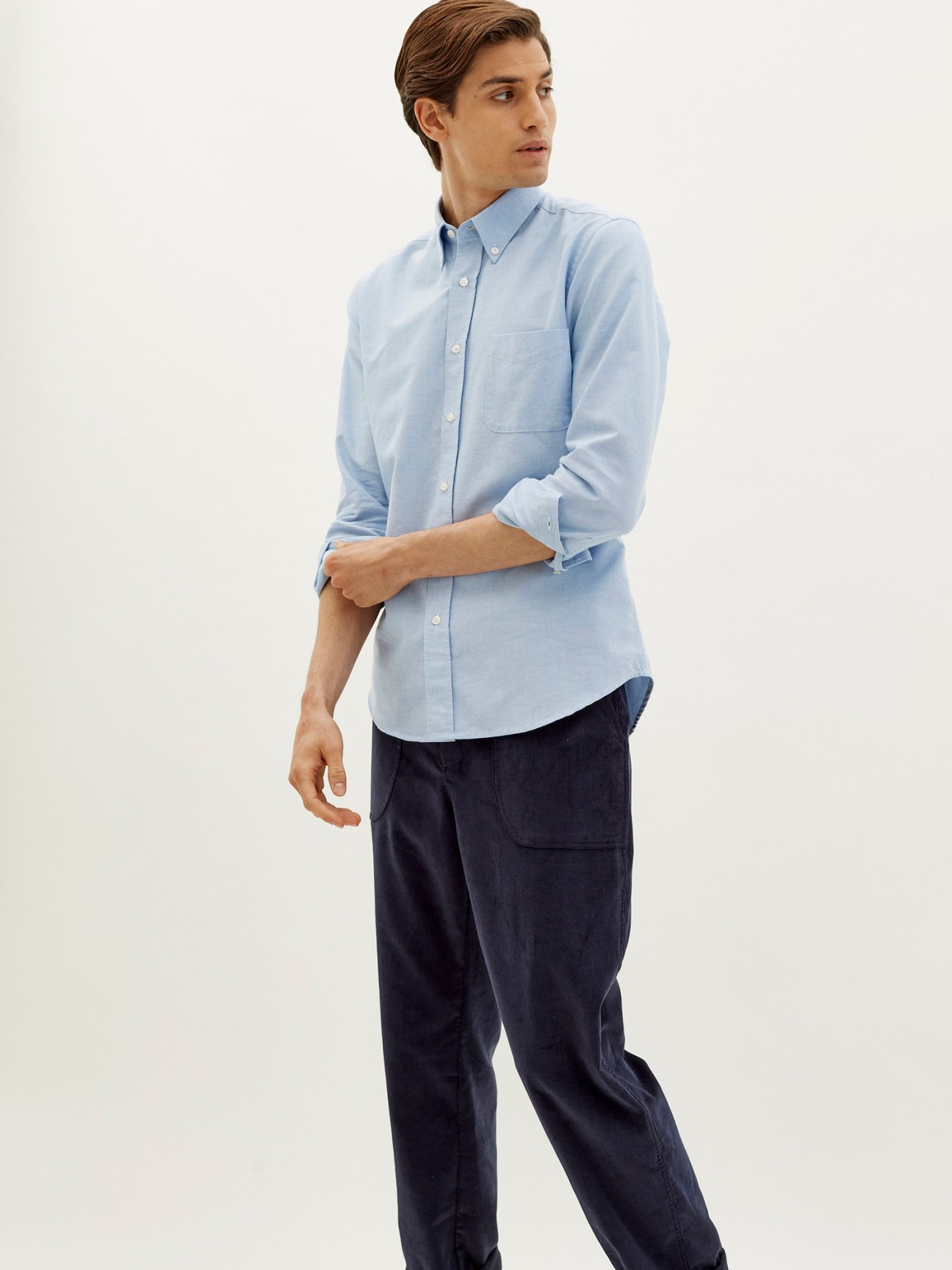 Man wearing a light blue button-down shirt by Trunk x Monocle with dark trousers.