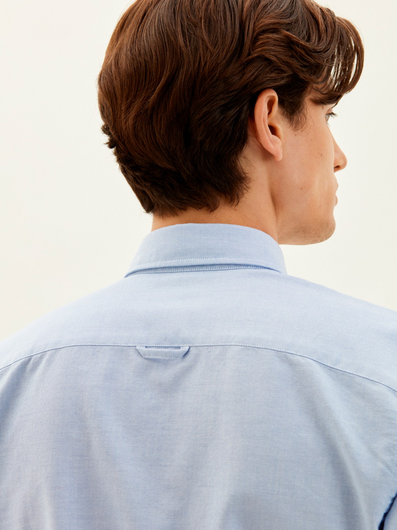 Man wearing light blue button-down classic shirt by Trunk x Monocle, shown from behind.